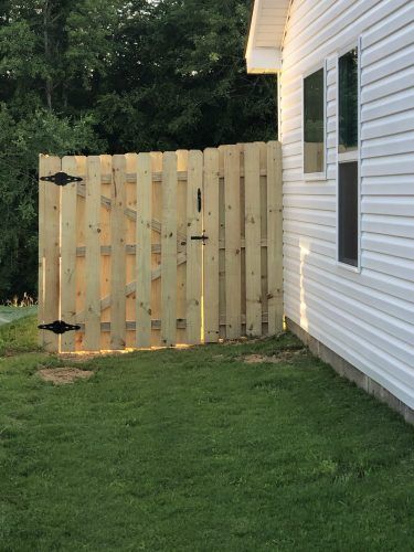 A wooden fence is sitting next to a white house.