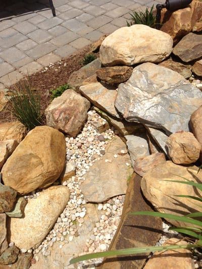 A pile of rocks and gravel on a patio next to a brick walkway.