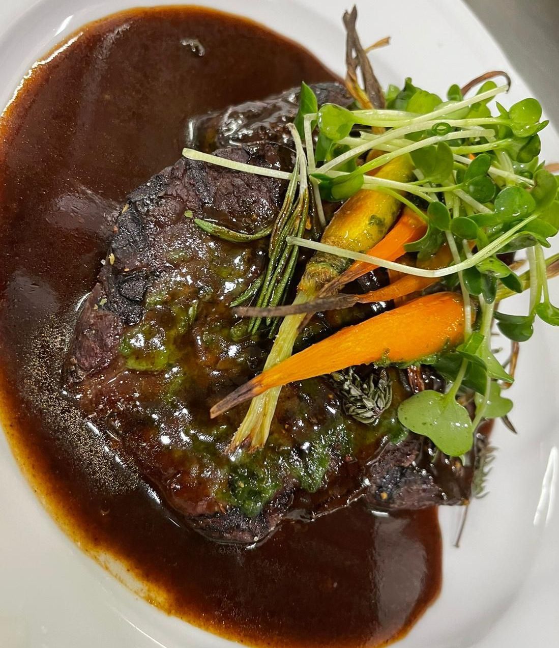 Ein weißer Teller mit einem Stück Fleisch und Gemüse