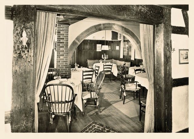 Ein Schwarzweißfoto eines Restaurants mit Tischen und Stühlen