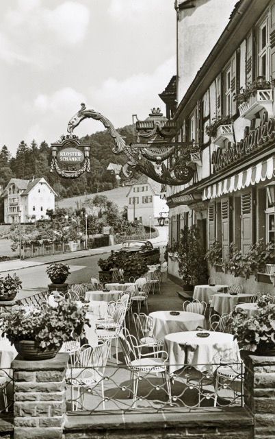 Ein Schwarzweißfoto eines Restaurants mit Tischen und Stühlen