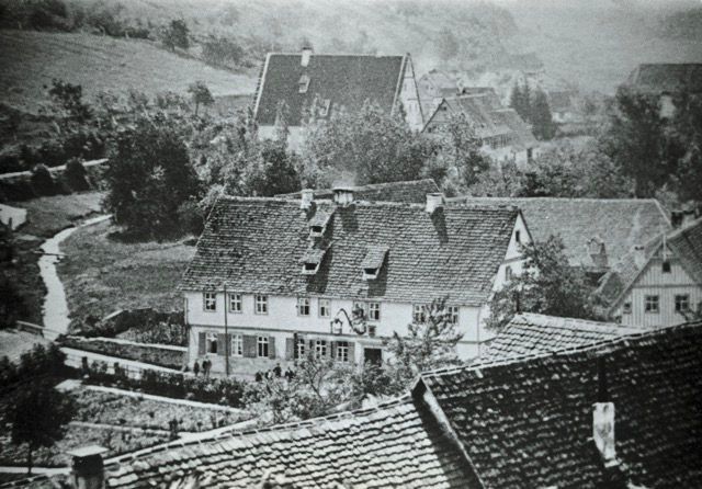 Ein Schwarzweißfoto eines Dorfes mit Häusern und Bäumen