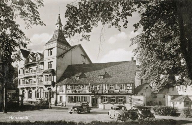 Ein Schwarzweißfoto eines großen Gebäudes mit davor geparkten Autos