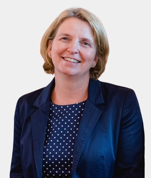 Barbara Wedner in einer blauen Jacke und einem gepunkteten Oberteil lächelt in die Kamera