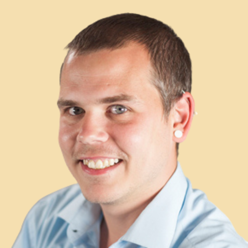 Man smiling, wearing a light blue button-down shirt.