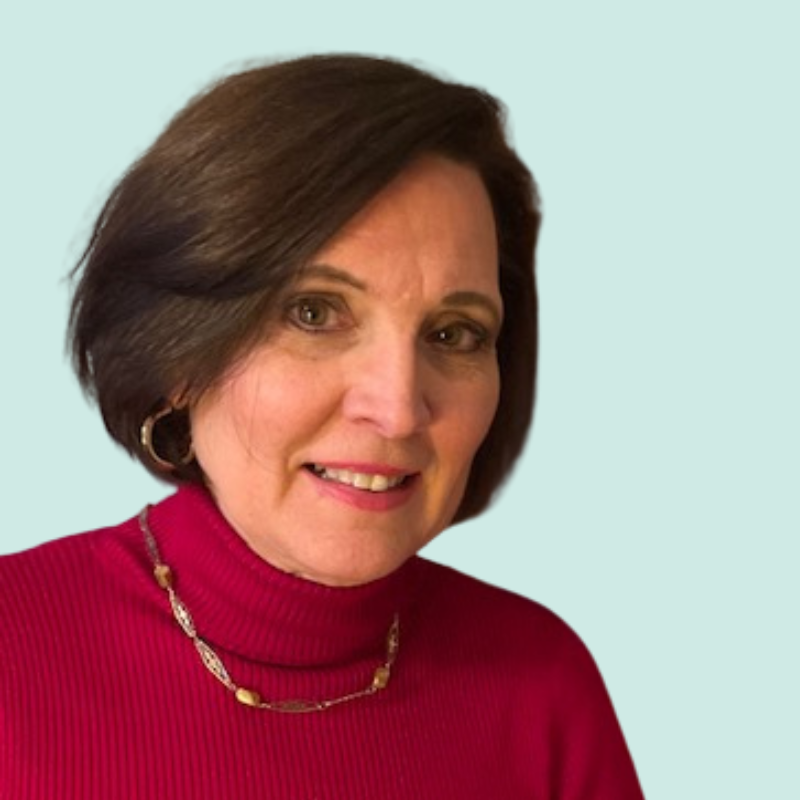 Woman with brown hair and a red turtleneck smiling, wearing earrings and a necklace.