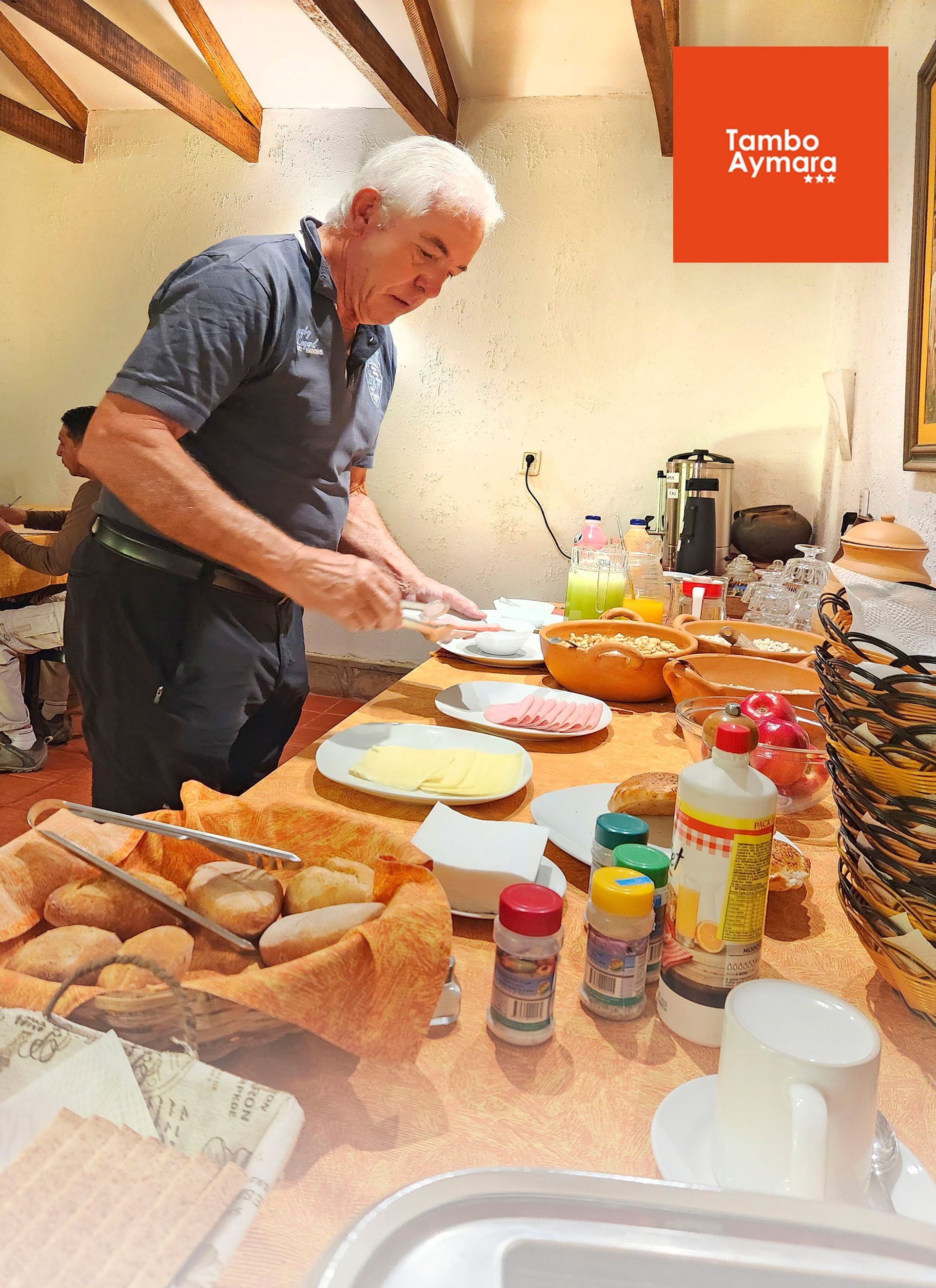 Persona preparando comida en una encimera de cocina desordenada con cuencos, tarros, pan y platos.