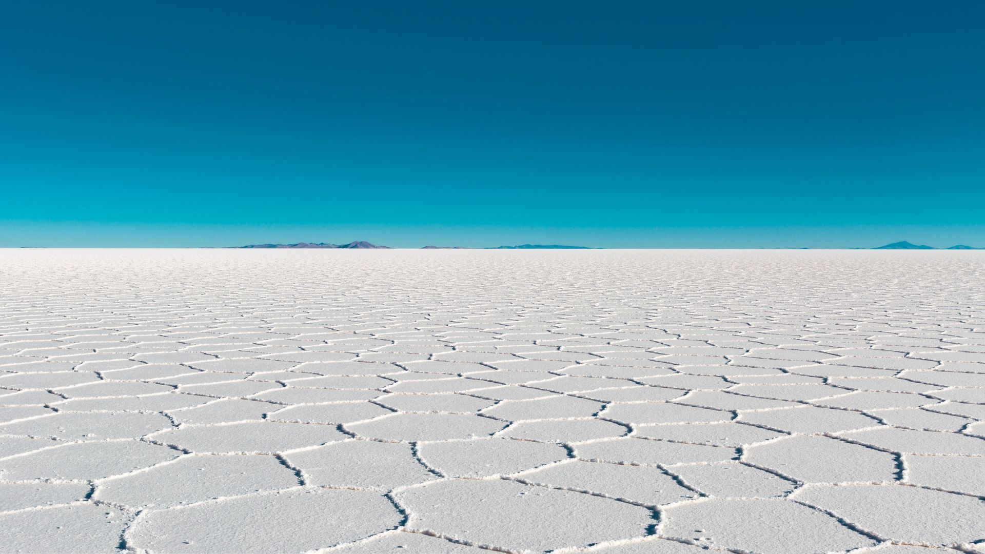 Salar blanco agrietado bajo un cielo azul claro
