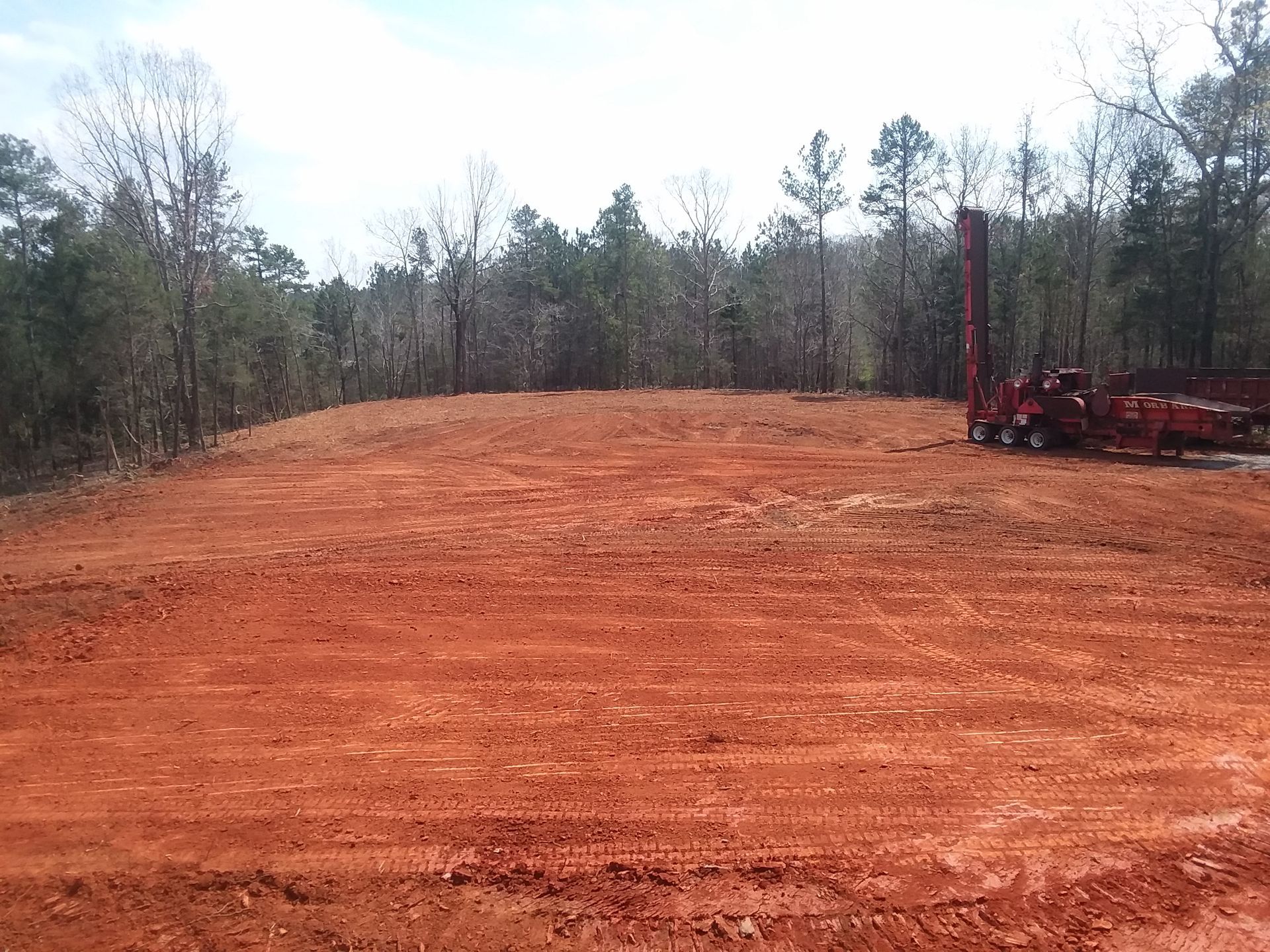 A group of construction vehicles are working on a dirt field.