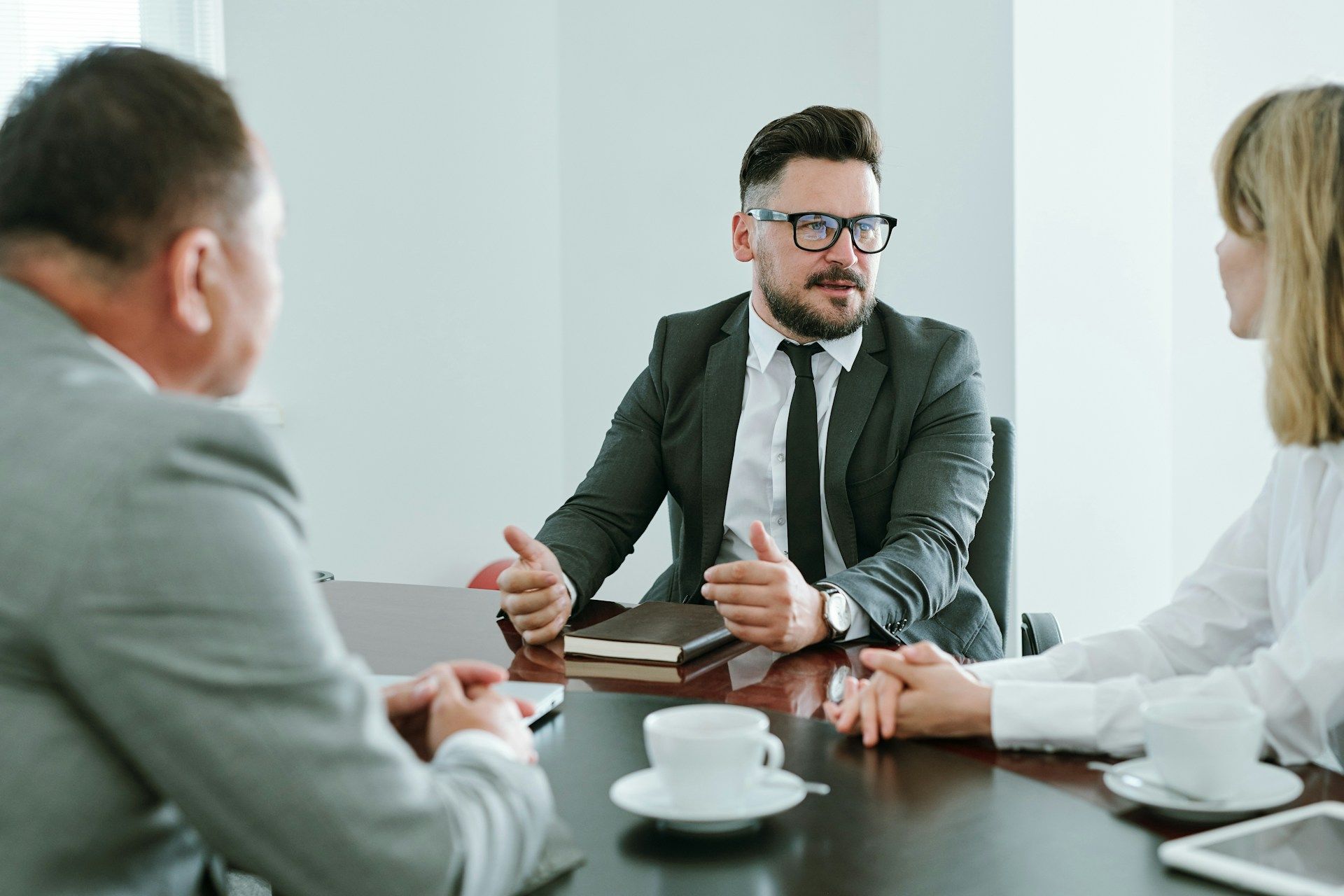 Business meeting with three people around a table, discussing documents in a bright office.