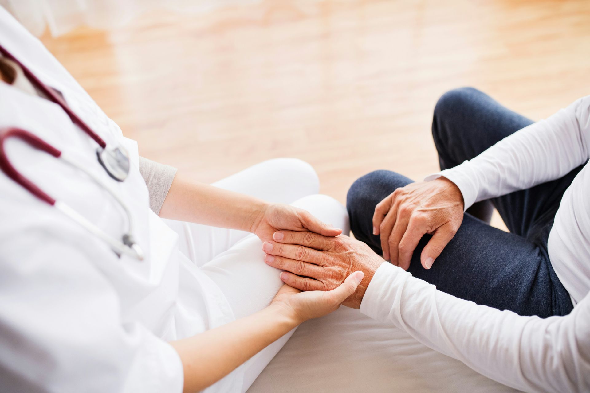 Doctor holding a patient’s hands during a supportive conversation in a bright clinic