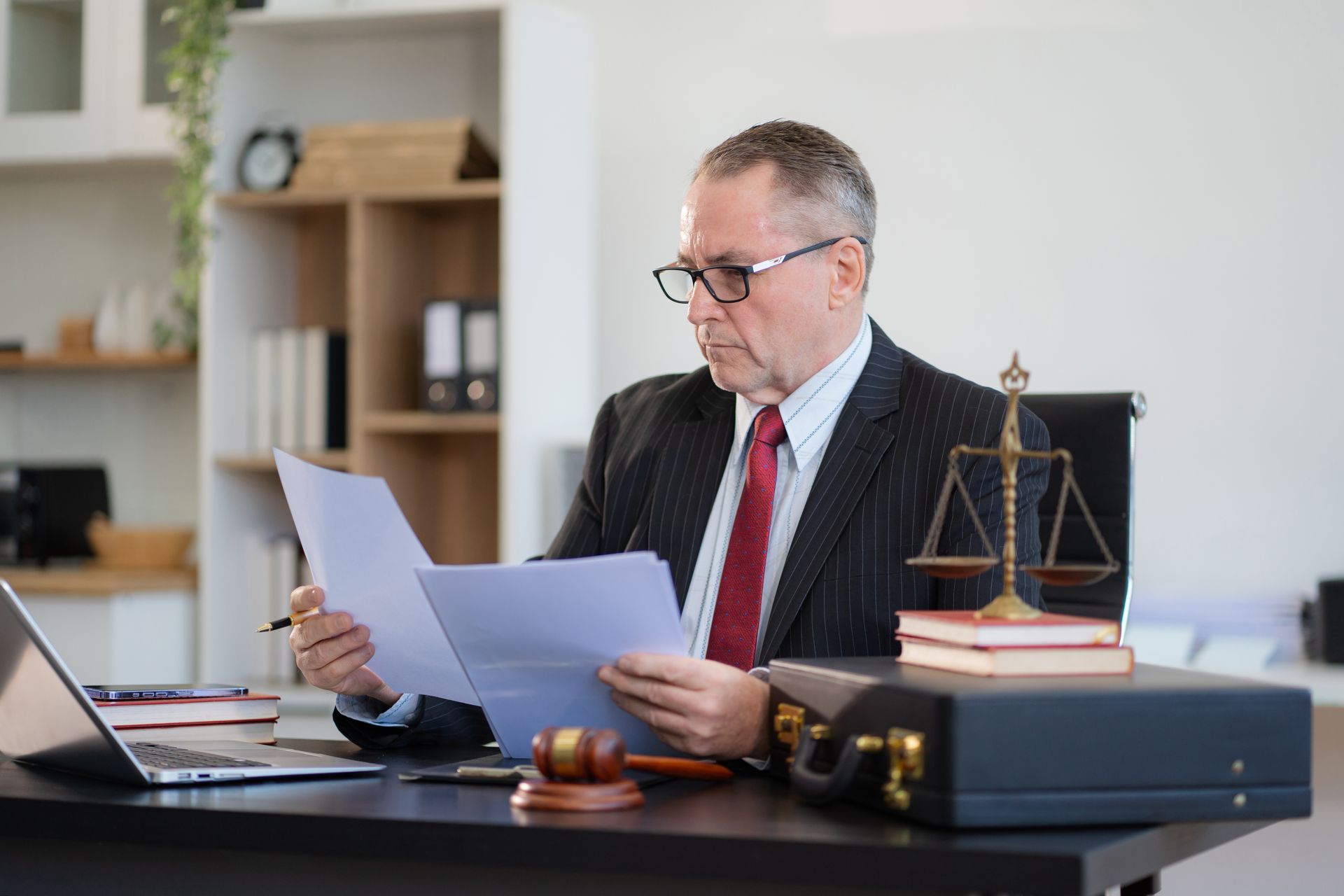 Lawyer reviewing documents at a desk with a gavel and scales of justice in an office