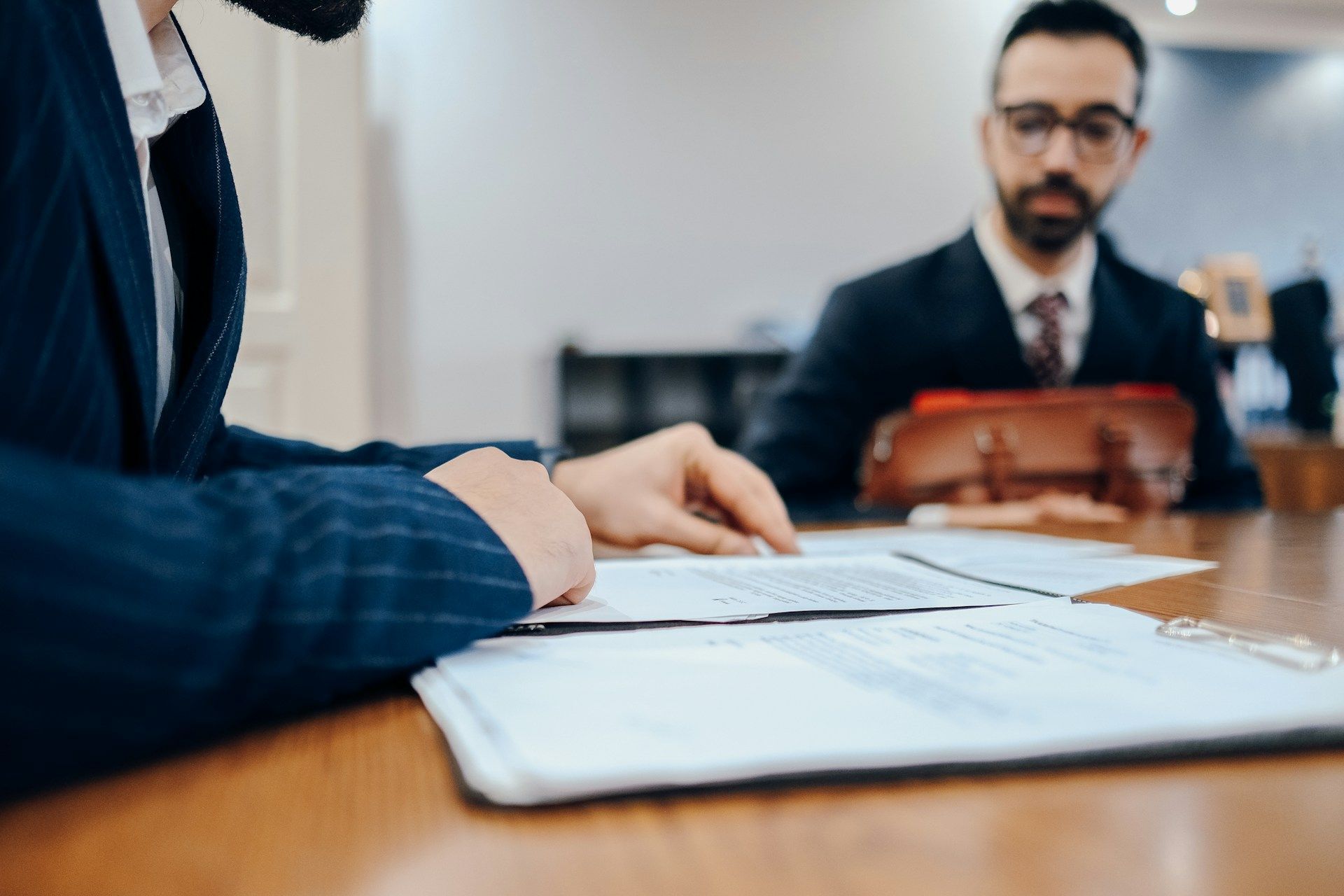 Business meeting with two suited people discussing documents at a table