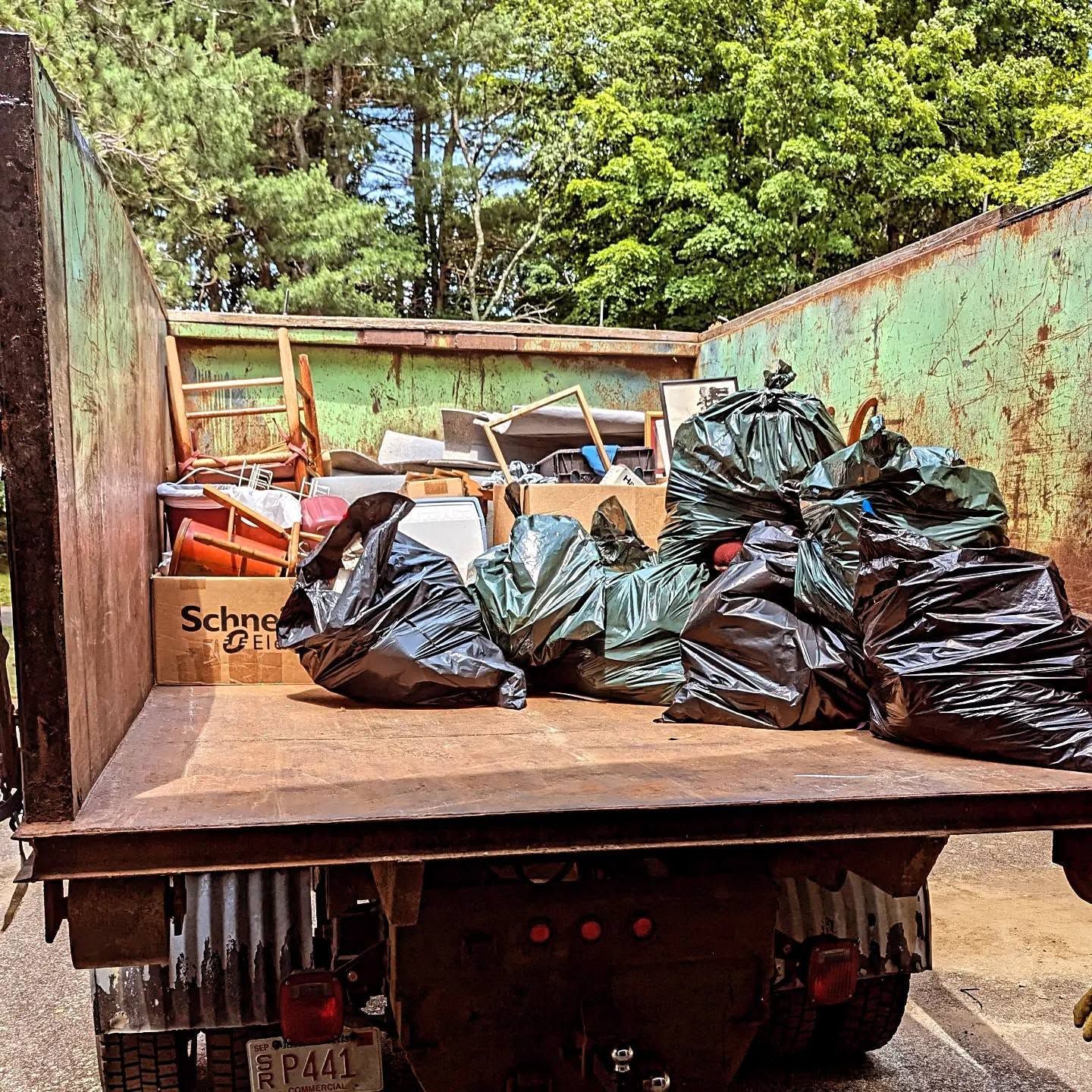 Dump truck bed loaded with black trash bags and cardboard outdoors