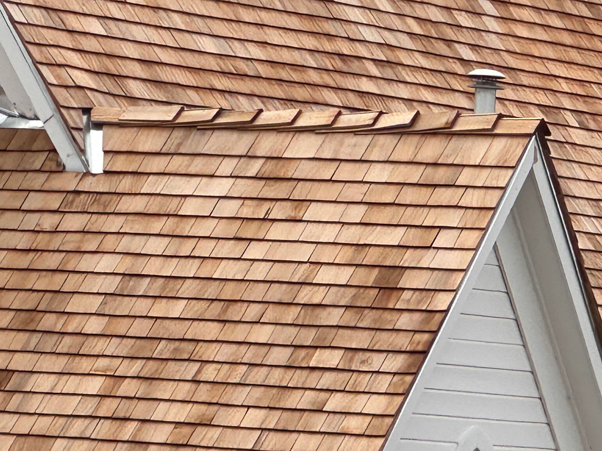 Aerial view of roof repair with workers replacing shingles on a white house