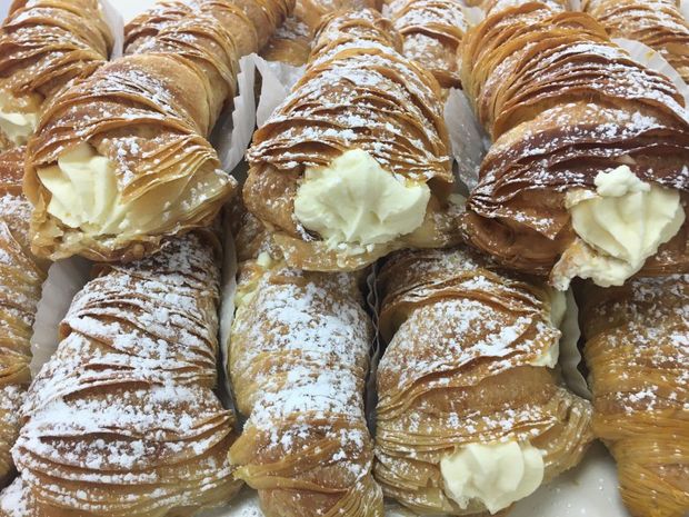 A bunch of pastries with powdered sugar on them are sitting on a table.