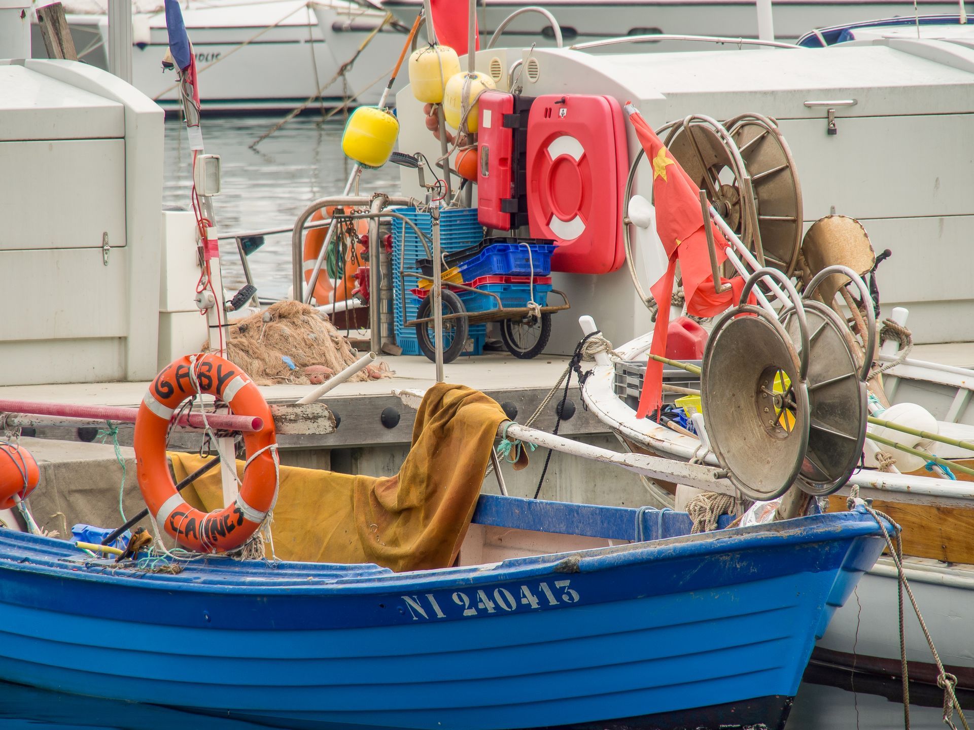A blue boat with a life preserver on the side is docked in a harbor.