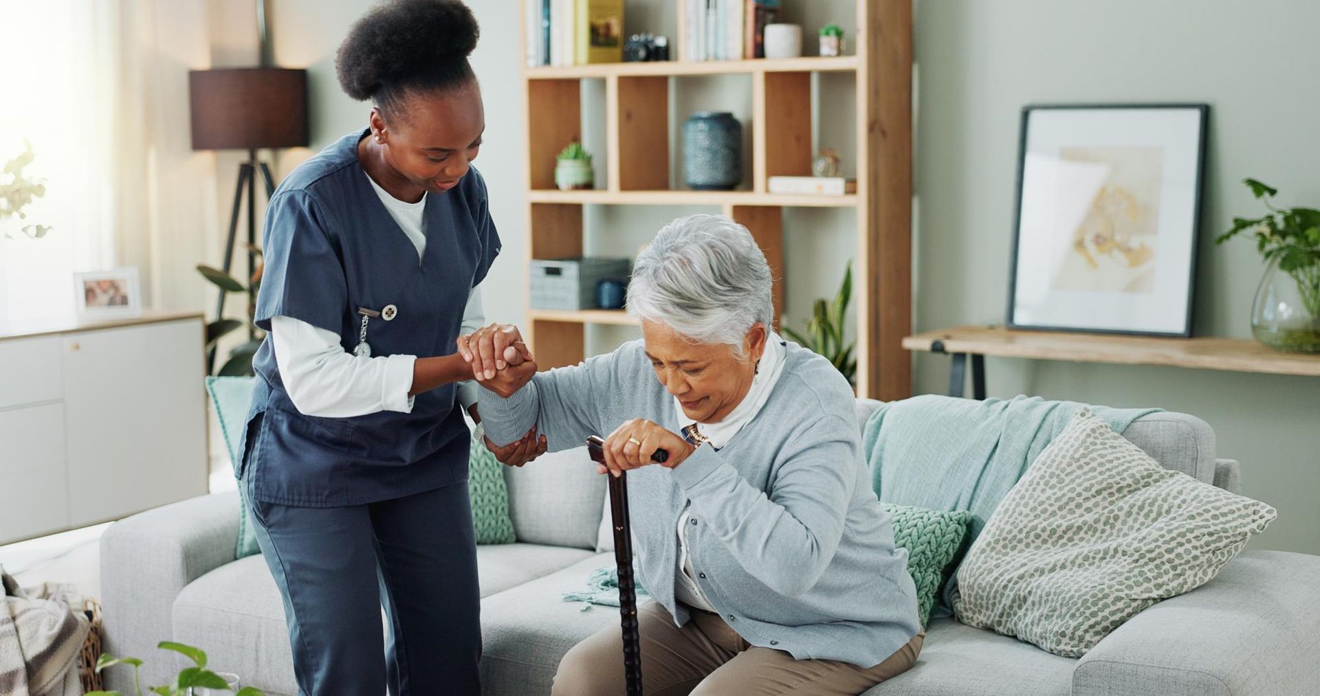 A nurse is helping an elderly woman with a cane.