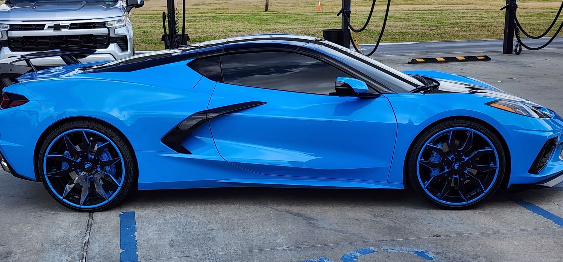 Bright blue Chevrolet C8 Corvette parked in an outdoor lot on a sunny day.