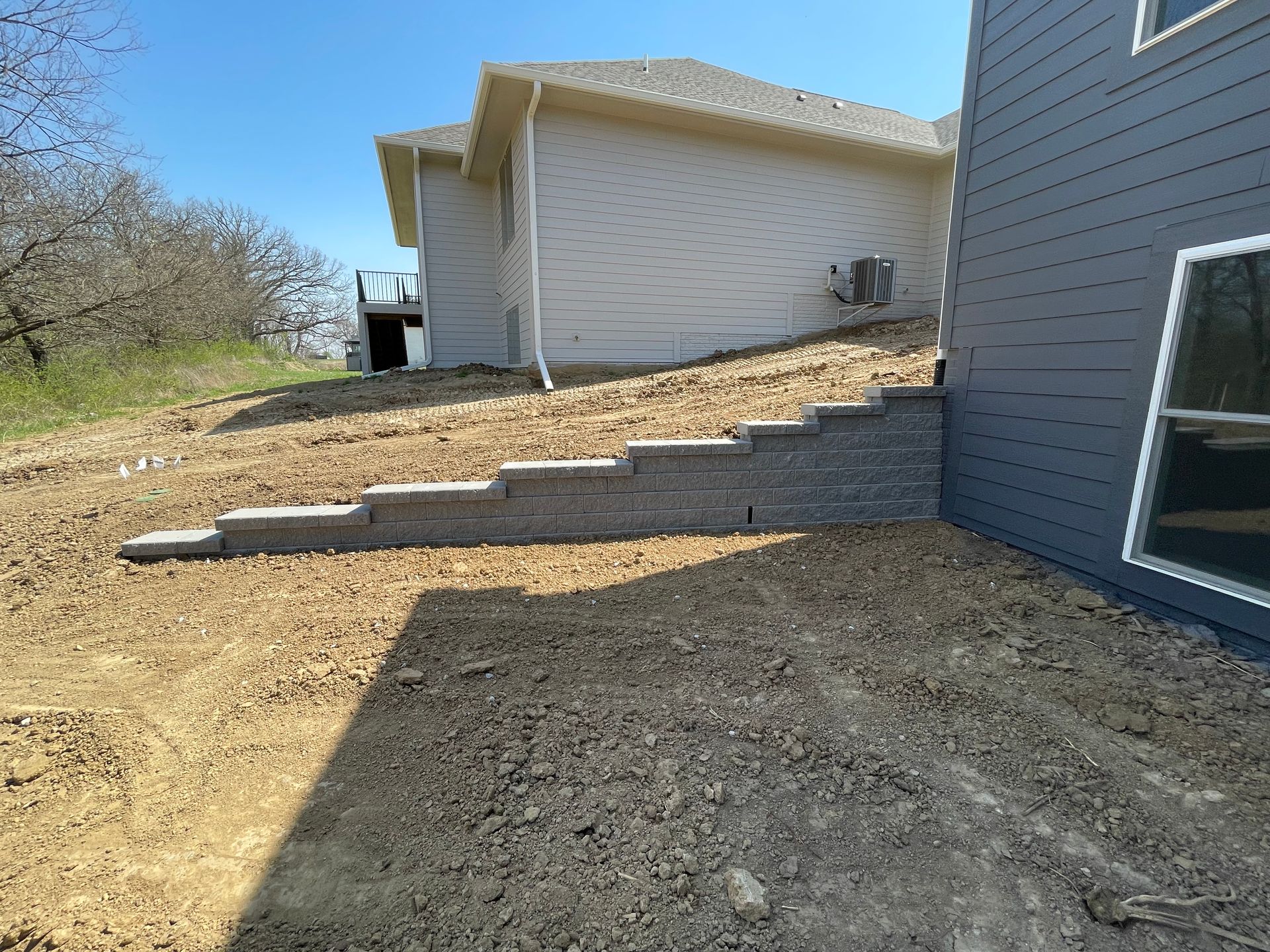 Backyard slope with concrete steps beside a white house and blue siding