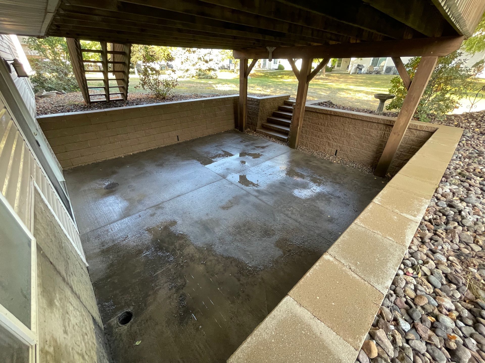 Covered concrete underpass with wet floor, brick walls, and steps leading up to a grassy area