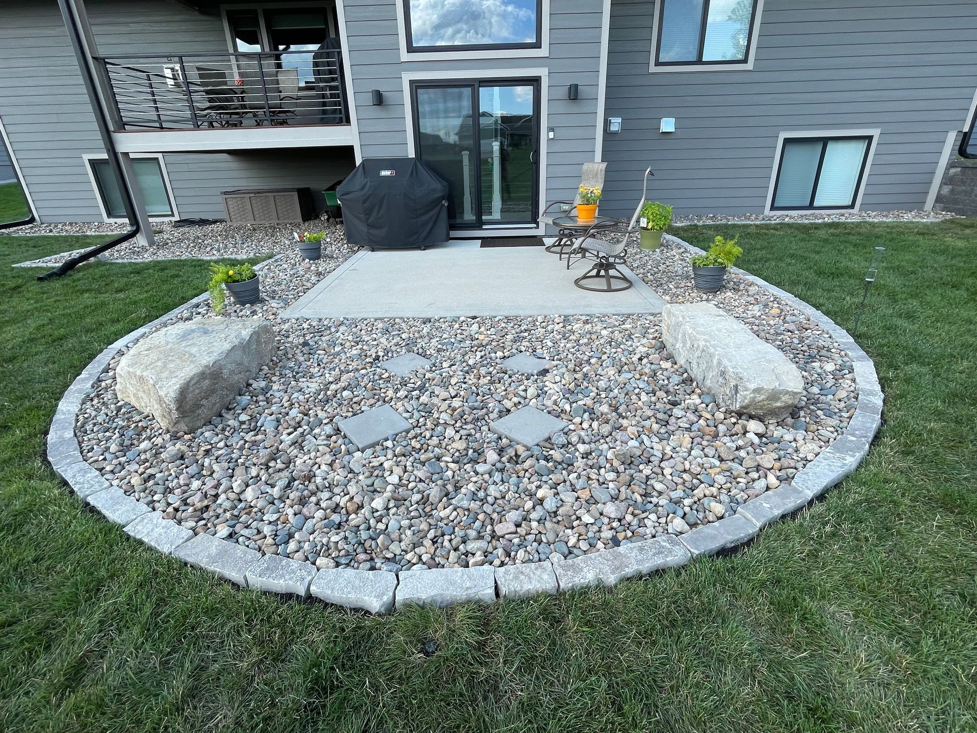 Front yard rock garden with a circular border, stepping stones, and patio in front of a house