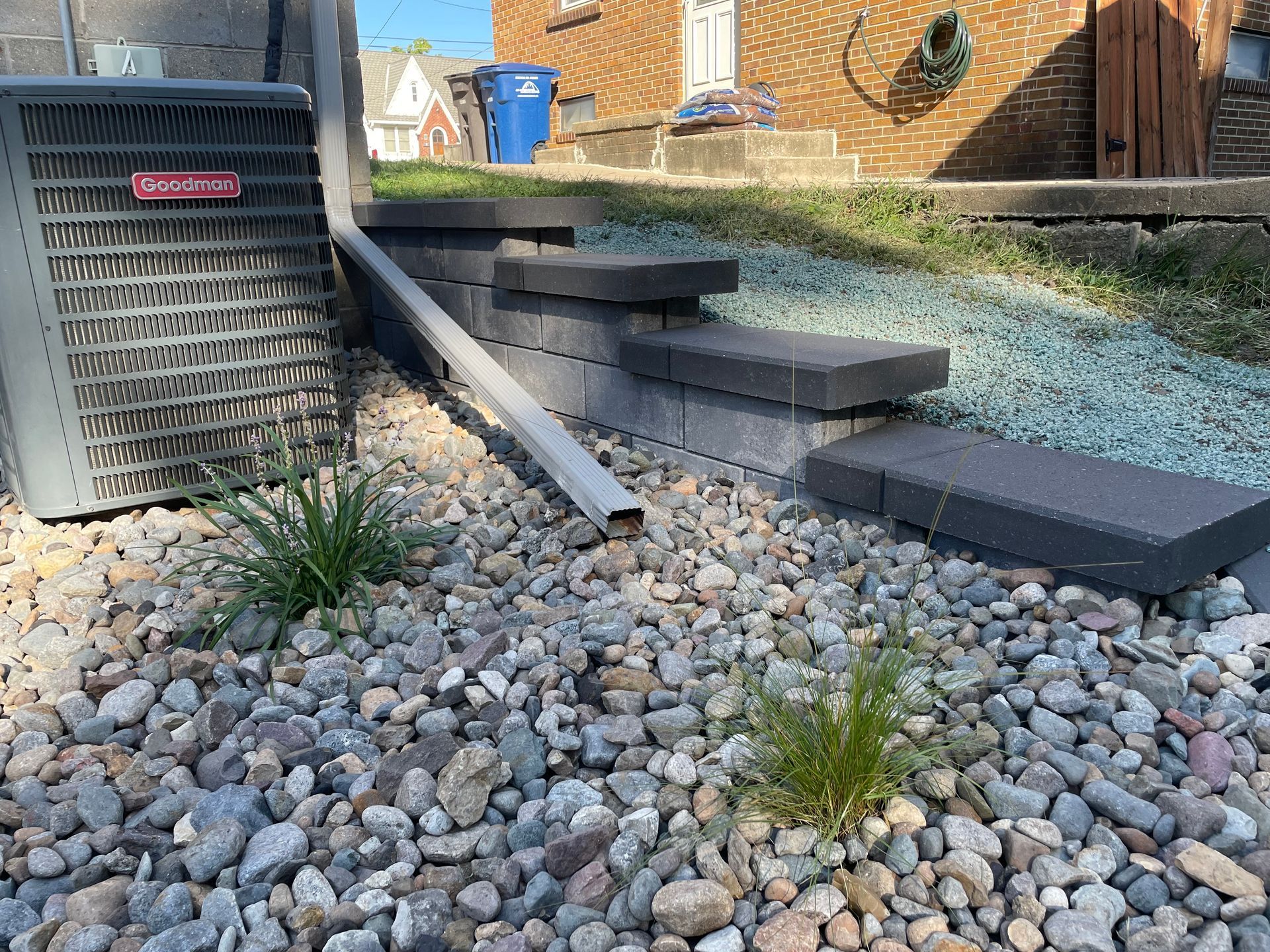 Stone steps and a metal ramp beside a house, leading over decorative gravel landscaping.