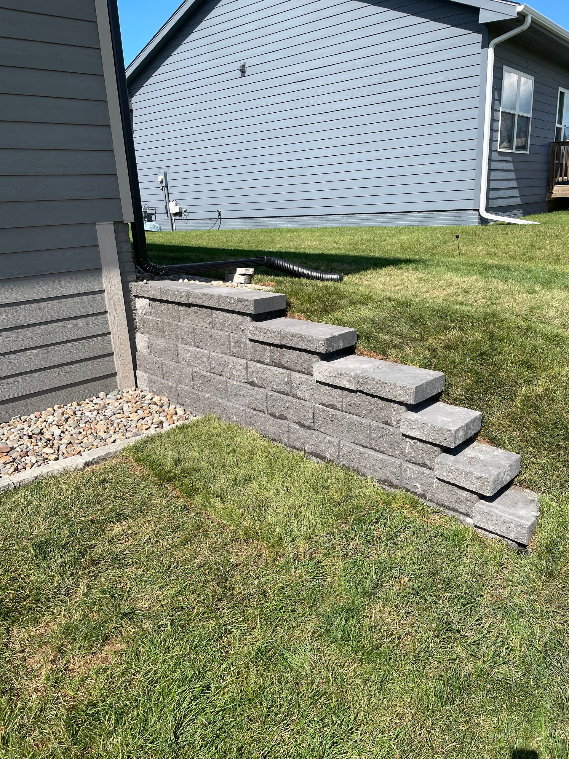 Concrete steps beside a house leading up a grassy slope to a side yard