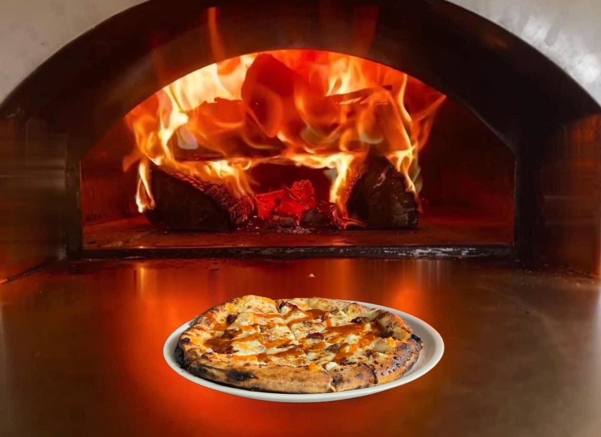 A pizza is being cooked in a wood fired oven.
