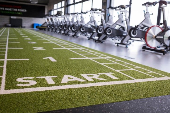 A gym interior featuring a green turf track marked
