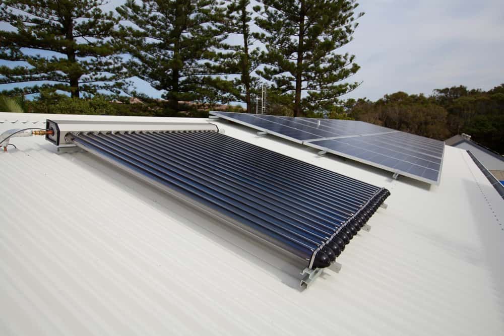 Two Solar Panels on a White Roof With Trees in the Background — Cool Heat Air Conditioning in Albion Park, NSW