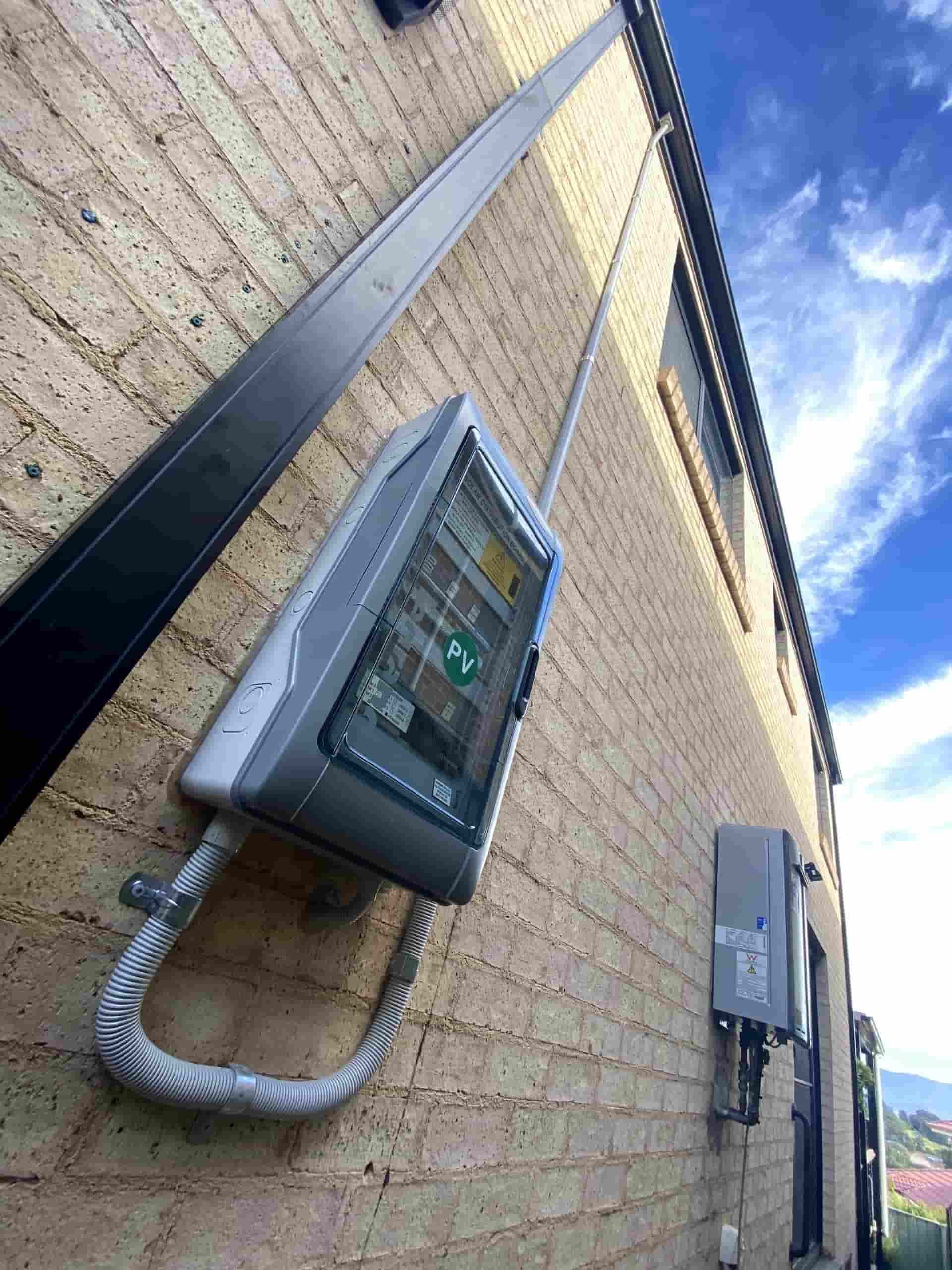 A PV is Hanging on the Side of a Brick Building — Cool Heat Air Conditioning in Albion Park, NSW
