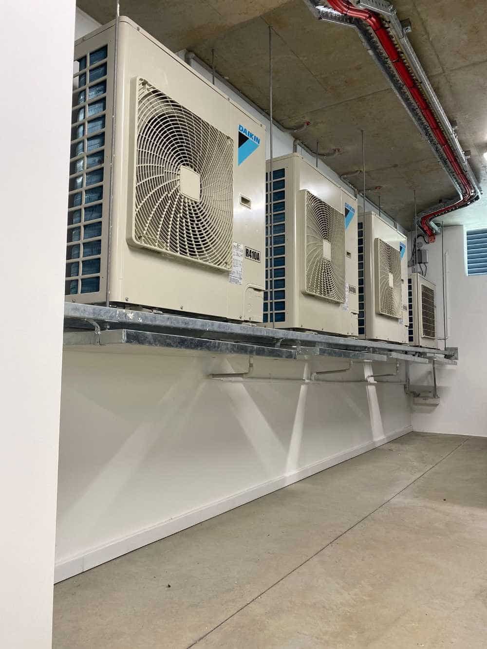 A Row of Air Conditioners Hanging From the Ceiling in a Room — Cool Heat Air Conditioning in Shellharbour, NSW
