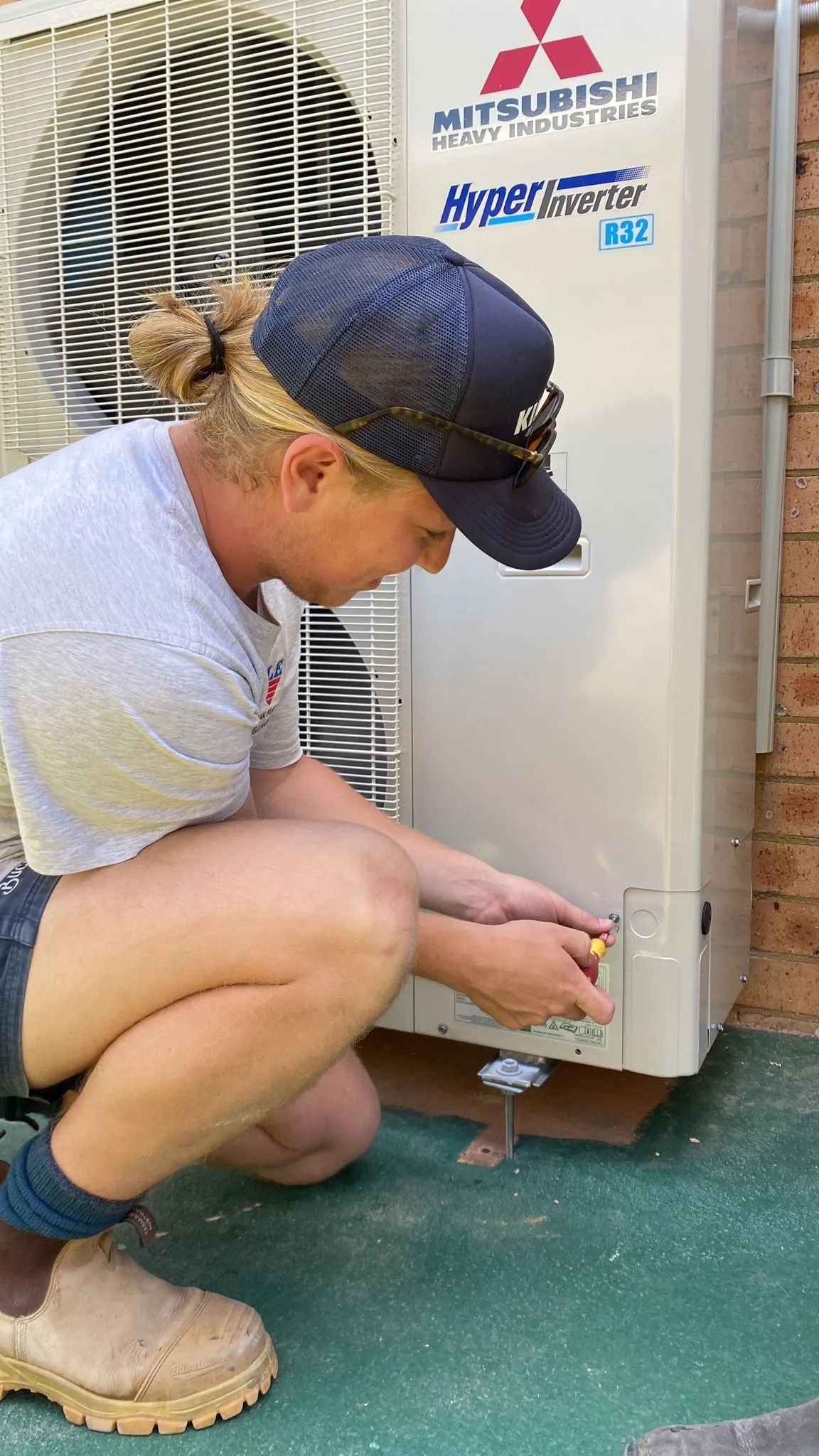 A person is working on an air conditioning unit with a screwdriver — Cool Heat Air Conditioning in Shellharbour, NSW