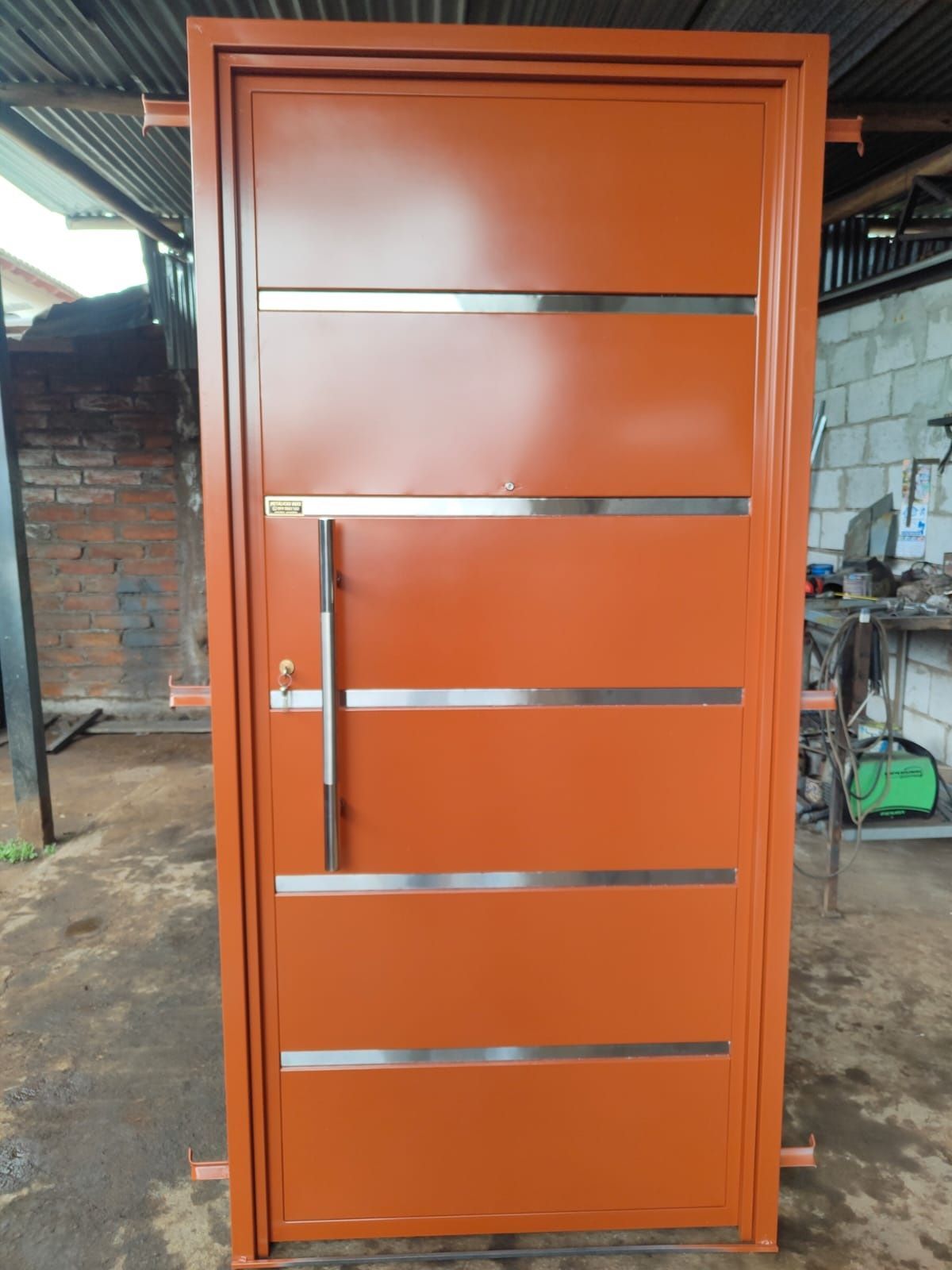 Una moderna puerta de acero naranja con cuatro franjas decorativas horizontales plateadas