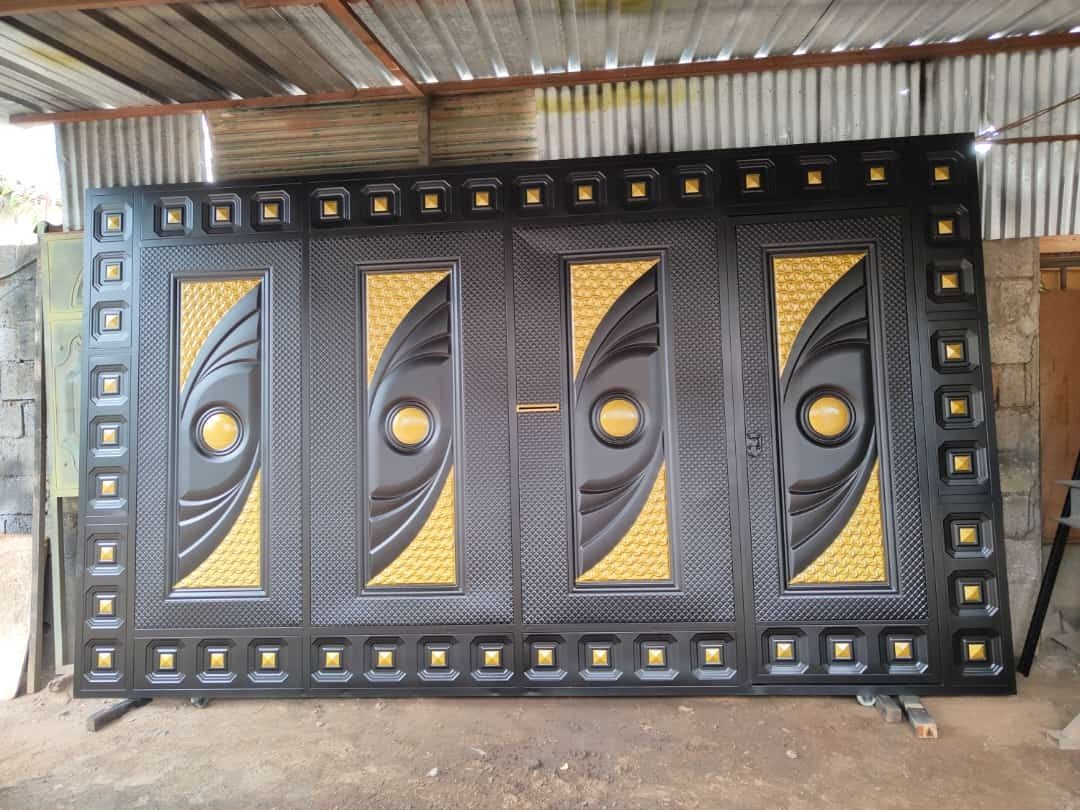 Una gran puerta de metal negro con detalles decorativos circulares dorados y paneles texturizados