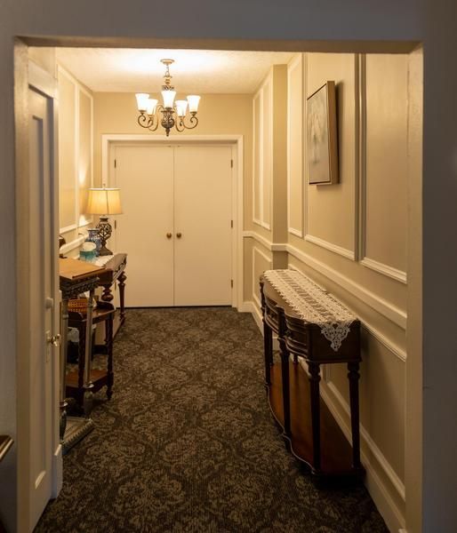 Hallway with double doors, chandelier, patterned carpet, and a console table against the wall.