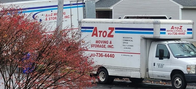 A to Z Moving & Storage truck parked beside a building with a red-leaf tree in front