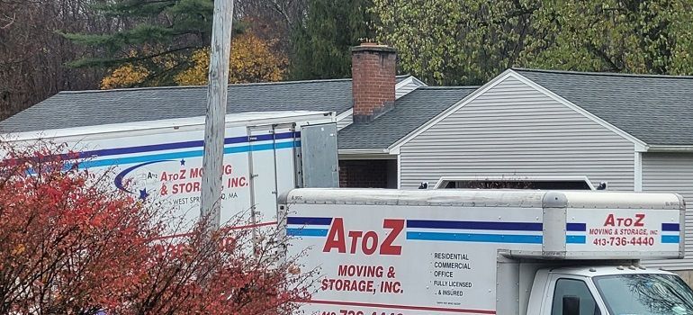 Two A to Z moving trucks parked beside a house in a suburban neighborhood