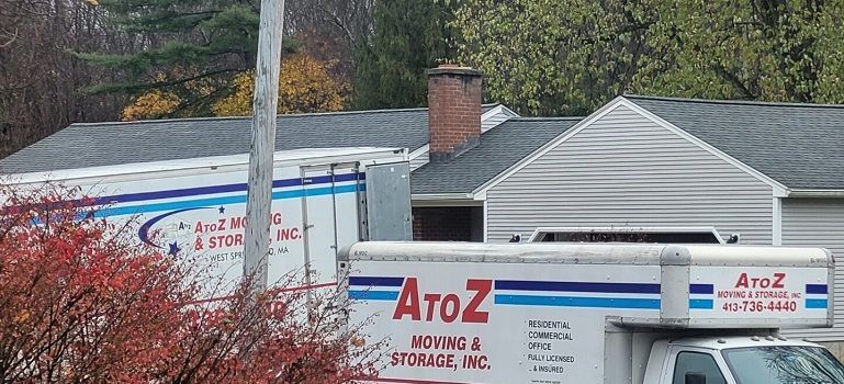 Moving truck with AtoZ Home & Office Movers branding parked by a house in a suburban driveway
