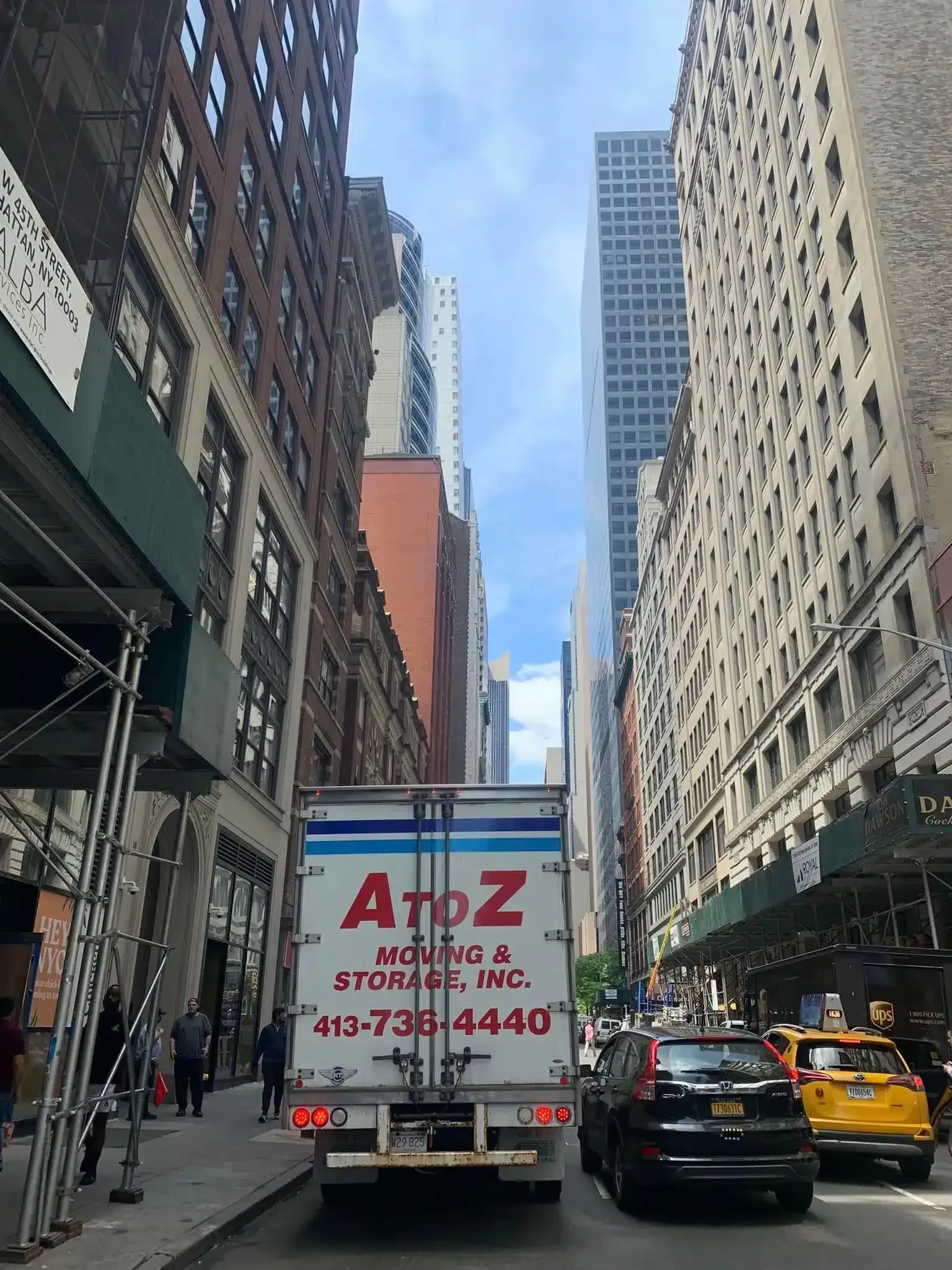 City street between tall buildings with a moving A to Z storage truck and traffic ahead