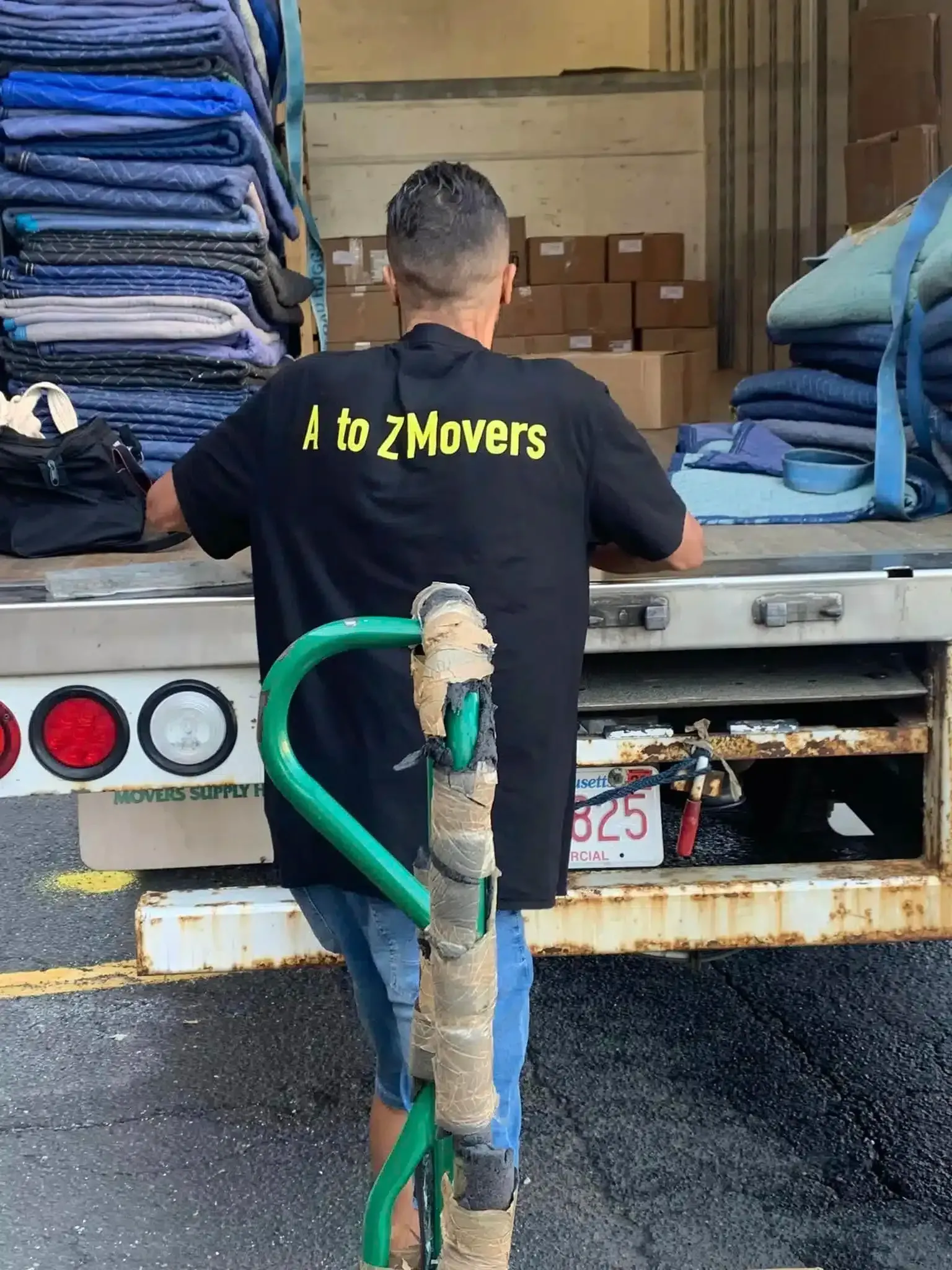 Mover loading blue folded items into a truck with a green hose in the foreground.