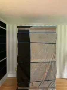 Tall black-and-white fabric wardrobe in a striped room, against a wall near a wooden floor.