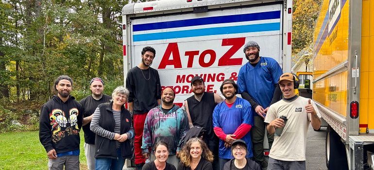 Group of people posing beside an A to Z moving truck in a wooded outdoor setting