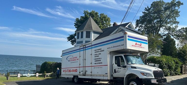 Moving truck parked beside a house near the ocean on a sunny day