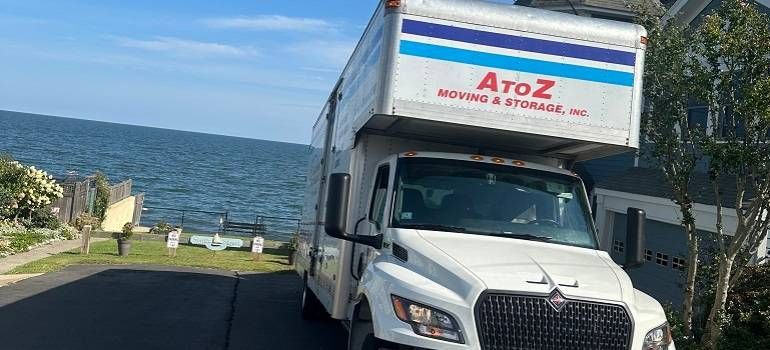 White delivery truck with AtoZ logo parked by the ocean on a narrow coastal road