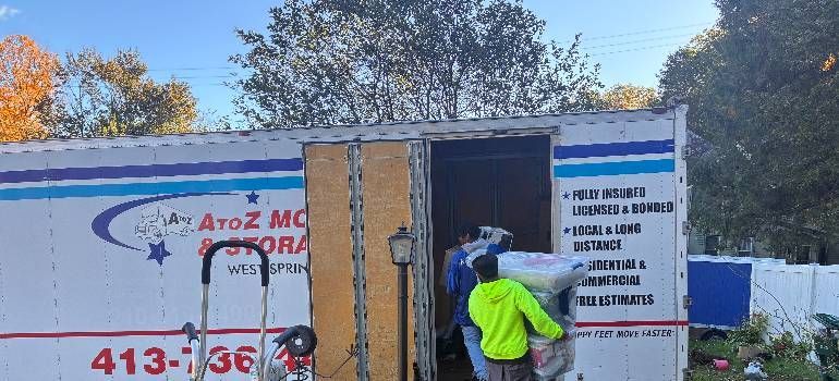 Worker in neon jacket opens the front of a white service truck with blue and red lettering.