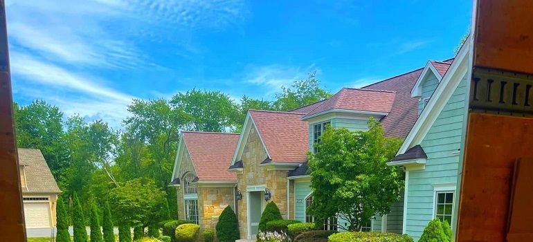 Row of suburban houses with red roofs and green trees under a bright blue sky