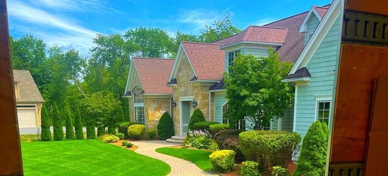 Sunny row of suburban homes with green lawns, trees, and curved sidewalks