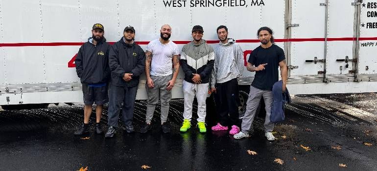 Six people posing in front of a white truck in West Springfield, MA, one with neon yellow shoes